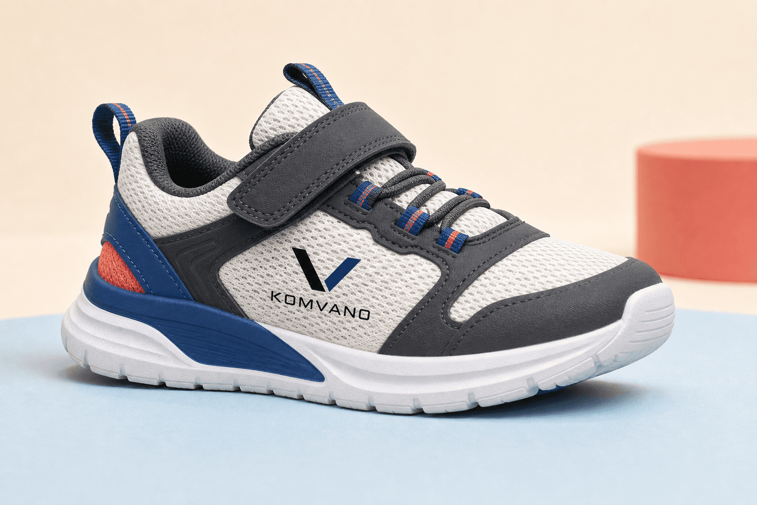 KOMVANO-branded children’s concept sneaker in white, charcoal, blue and coral.